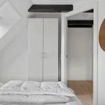 Bedroom with sloped ceiling, white bed, and wardrobe. Round mirror on the wall.
