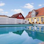 A pool with a view of yellow and red houses with red tiled roofs.