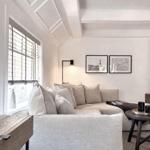 Ein Wohnzimmer mit Sofa, Fenster und Wandbildern.