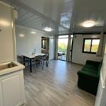 Kitchen with sink, dining table, sofa, and refrigerator. Passage to terrace with view of green areas.