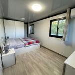 Bedroom with bed, wardrobe, and window. Wood floor and ceiling light.
