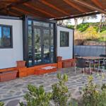 Patio with seating under roof, pool in background, plants and stone paving