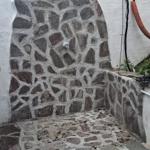 Stone shower with arched design and faucet on the wall.