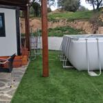Outdoor area with pool, table and chairs on stone and artificial grass.