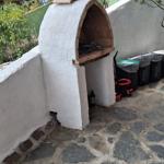 Outdoor area with stone paving and white oven. Background with trees and walls.