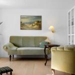 Ein Wohnzimmer mit grünem Sofa, Sessel und Bücherregal an der Wand.