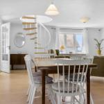 Esszimmer mit Tisch, Stühlen und Blick auf Wohnzimmer mit Wendeltreppe.