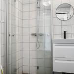 Dusche mit Glaswand, Waschbecken und Spiegel an der Wand.