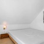 Schlafzimmer mit Dachschrägen, Bett, Wandlampe und Poster an der Wand.