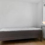 Ein Schlafzimmer mit Bett, Fenster und Schrank. Die Wand ist weiß.