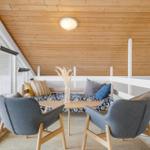 Zimmer mit Holzdecke, zwei grauen Stühlen und einem Sofa mit Kissen.