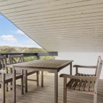 Terrasse mit Tisch und Stühlen, Blick auf Dünen und Himmel.