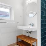Badezimmer mit Waschbecken, Spiegel, Fenster und blauen Fliesen.