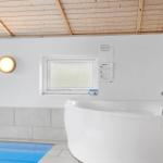 Bad mit Whirlpool, Dusche und Fenster. Holzdecke und weiße Wände.
