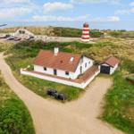 Wohnhaus mit rotem Dach und rotem Schuppen, nahe Leuchtturm und Strand.