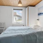 Schlafzimmer mit Bett, Fenster und Holzdecke. Wandbild und Schreibtisch sind sichtbar.