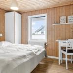 Schlafzimmer mit Holzwand, Bett, Schreibtisch und Fenster.