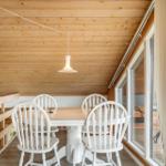 Essbereich mit weißem Tisch und Stühlen unter Holzdecke mit hängender Lampe.