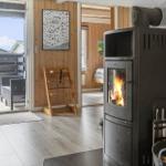 Kaminofen mit brennendem Holz, Terrasse mit Sitzgelegenheiten und Holzwand im Hintergrund.