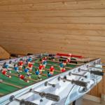 Fußballtisch in einem Holzhaus mit geneigtem Dach und Sitzgelegenheit.
