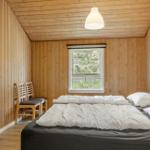 Schlafzimmer mit Holzwand, Bett, Fenster und Stühlen.