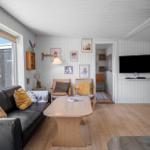 Wohnzimmer mit Sofa, Tisch, Kamin und Fernseher an der Wand.