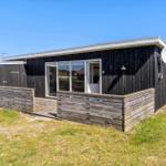 Moderne Holzhütte mit Terrasse und Satellitenschüssel im Freien.