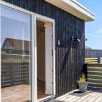 Schwarze Holzwand mit Glasfront und Terrasse. Pflanze im Topf neben der Tür.