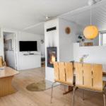 Wohnzimmer mit Esstisch, Kamin und Fernseher. Holzfußboden und weiße Wände.