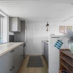 Küche mit grauen Schränken, Holzoberfläche und Fenster. Holzfußboden und weiße Wände.