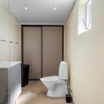 Badezimmer mit Toilette, Waschbecken und Duschbereich mit Glaswand.