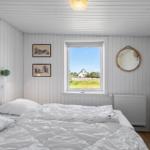 Schlafzimmer mit weißem Bett, Fensterblick und Wandbildern.
