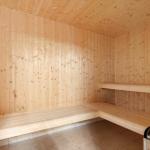 Sauna with wooden walls and benches, tiled floor and wood stove