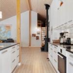 Kitchen with white cabinets and wooden floor. Living room with sofa and map in background.