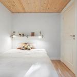 Bedroom with bed, wooden ceiling, and wall shelf with lamps.