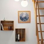 Wall with wooden shelves, picture, and ladder. Two pendant lights hang above.
