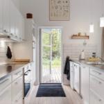 Kitchen with white cabinets, stainless steel countertop, and door to balcony.