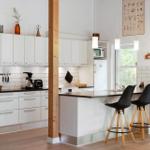 Kitchen with white cabinets, black countertop, and wooden stools at the counter.