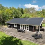 Modern wooden cabin with large deck, garden furniture, and view into the forest.