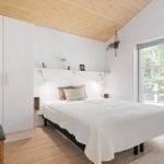 Bedroom with white bed, wooden ceiling, and window to the garden