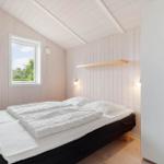Schlafzimmer mit Doppelbett, Fenster und Kleiderschrank.