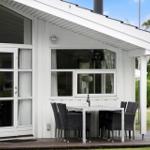Wohnung mit Terrasse, Tisch und Stühlen. Weiße Fassade und Holzdecke.