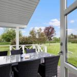 Terrasse mit Tisch und Stühlen, Blick auf grünen Rasen und Bäume.