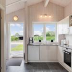 Küche mit weißen Schränken, Fenster und Tür zum Garten