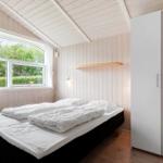 Schlafzimmer mit Doppelbett, Fenster und Kleiderschrank. Holzwände und -decke.