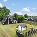 Schwarze Holzhäuser mit Garten und Spielplatz unter blauem Himmel.