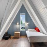Ein Schlafzimmer mit Dachschrägen, Bett, Fenster und Korb.