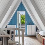 Dachgeschoss mit blauer Wand, weißen Schränken und Spielzeugküche. Tür führt nach draußen.