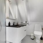 Badezimmer mit Dusche, Waschbecken und Toilette unter schrägem Dach