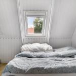 Schlafzimmer mit Dachfenster, weißer Holzwand und Bett mit Musterdecke.